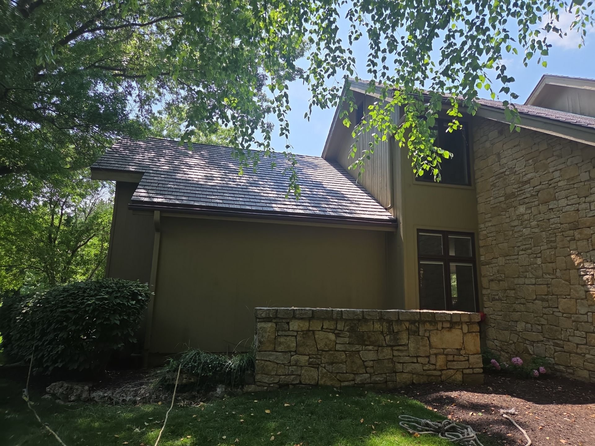 A house with a brown roof and exterior walls, surrounded by trees and greenery.