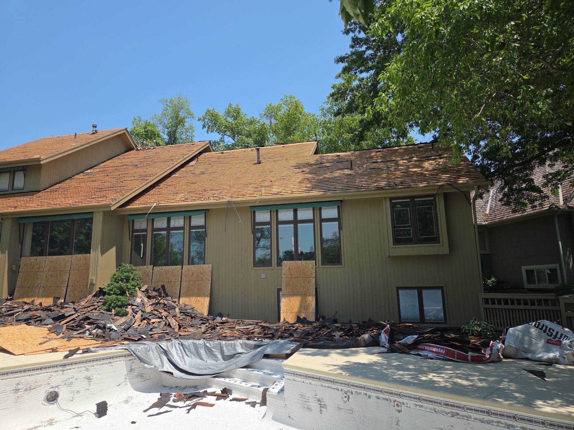 Building under construction; roof partially removed; debris in pool and on the ground. Sunny day.