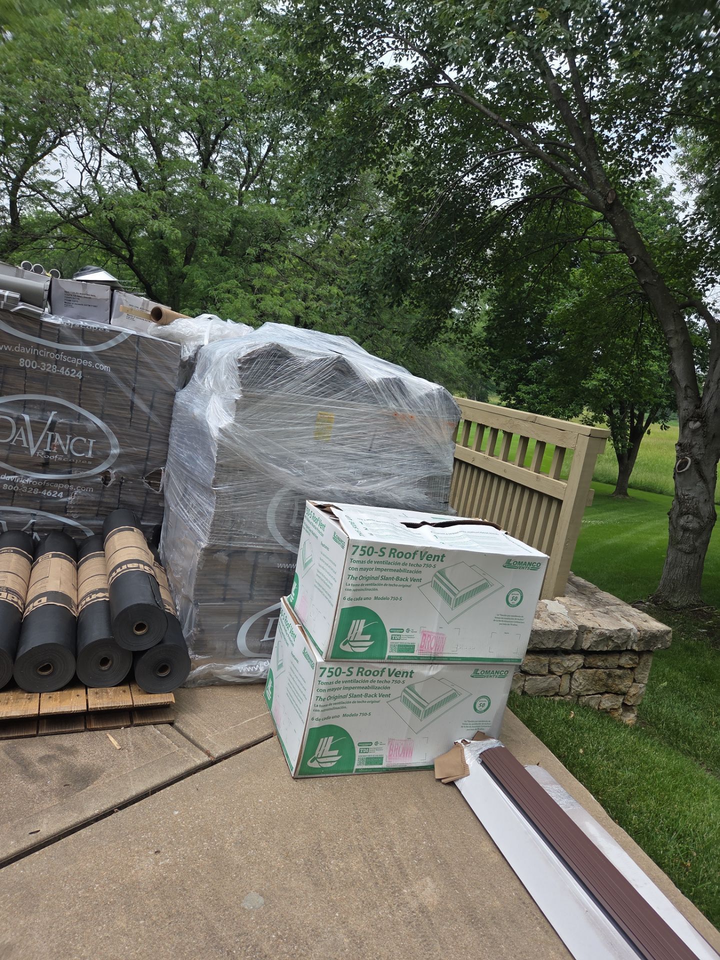 Supplies on a roof for a construction project, including pavers, roofing materials, and boxes.