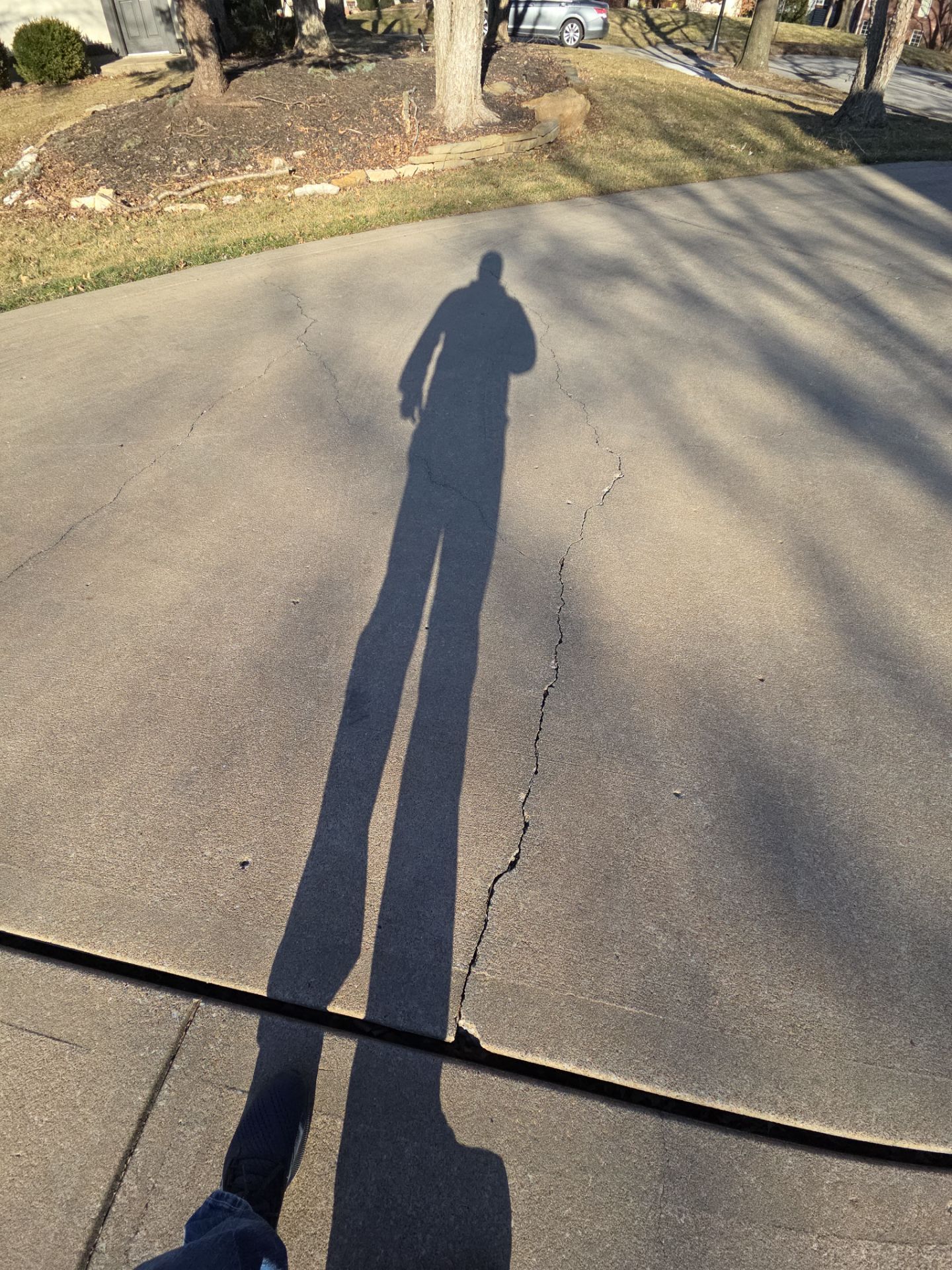 A long shadow of a person on asphalt road, cast by the sun.