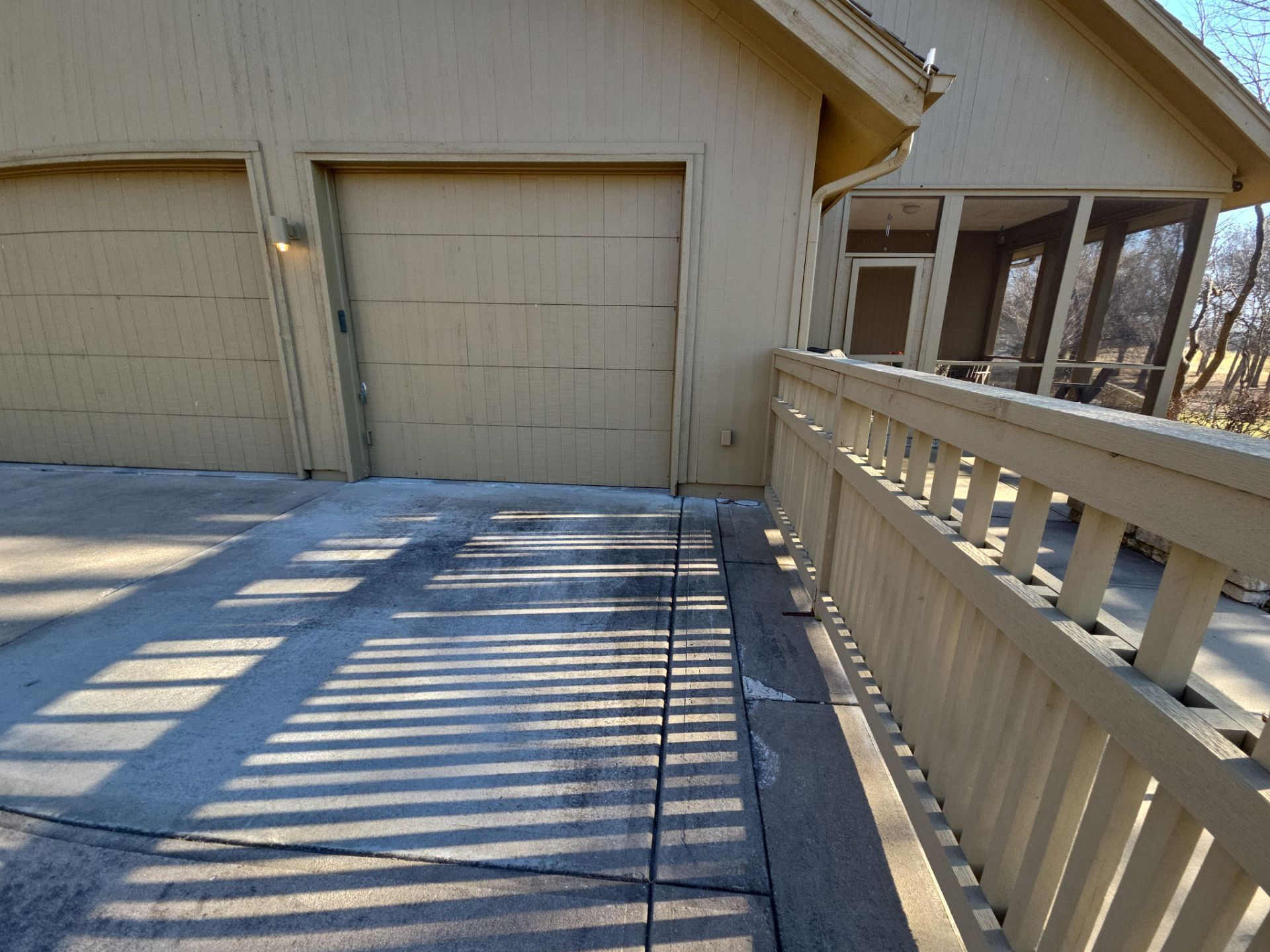 Garage and deck with a concrete walkway and railing.