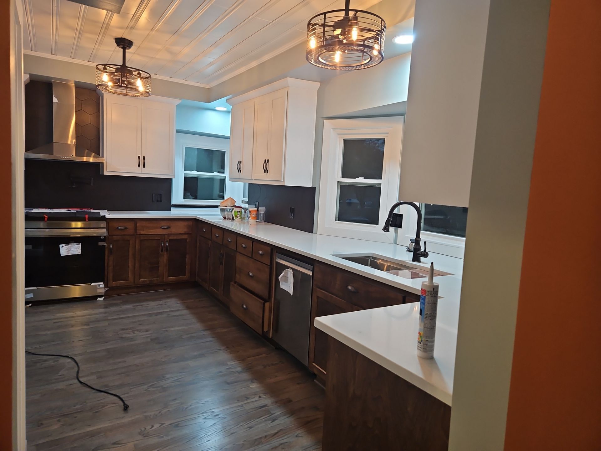 Kitchen with white countertops, dark wood cabinets, and two ornate light fixtures.