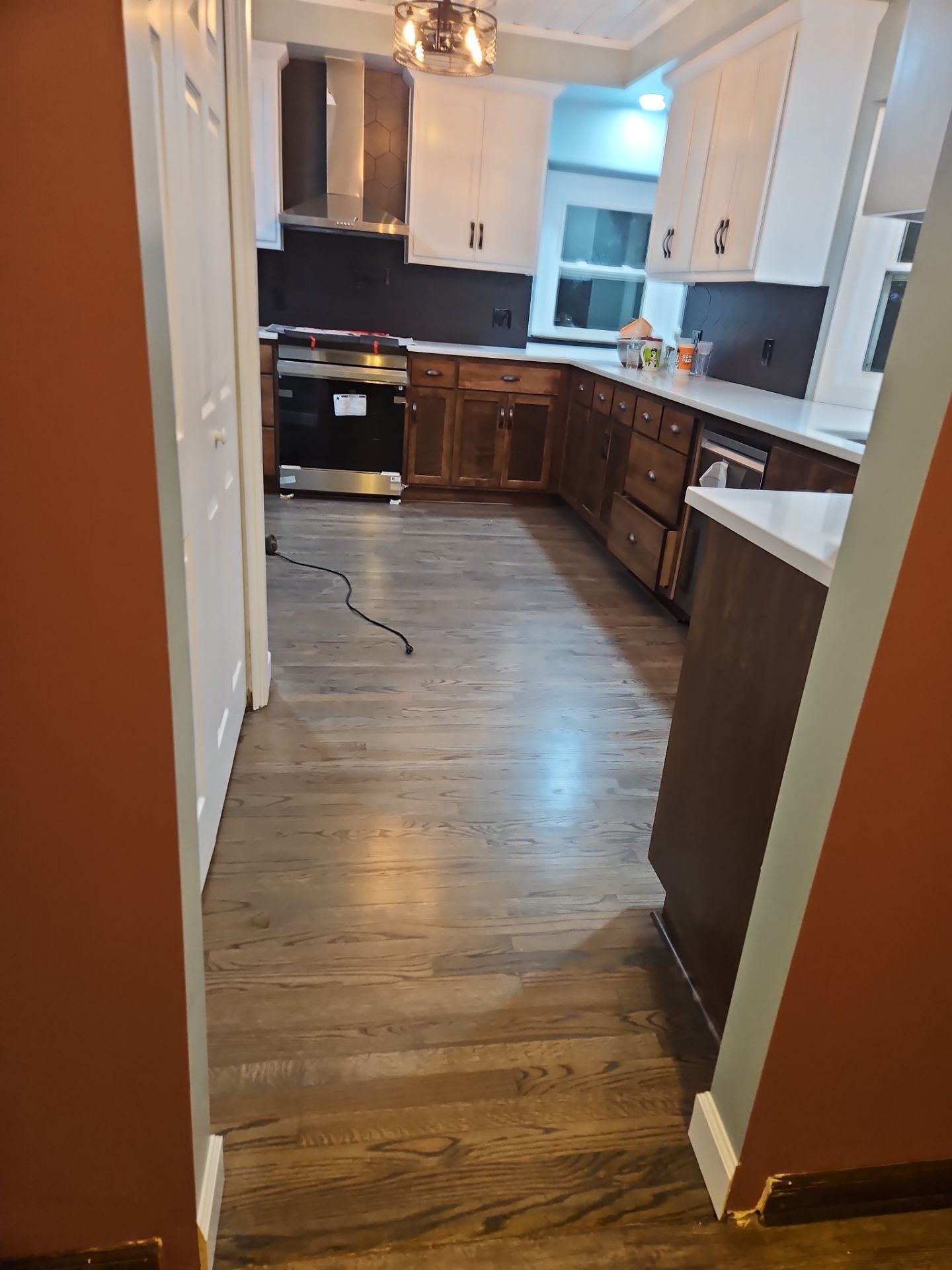 Kitchen renovation with wood-look flooring, two-tone cabinets, and a stainless steel range.