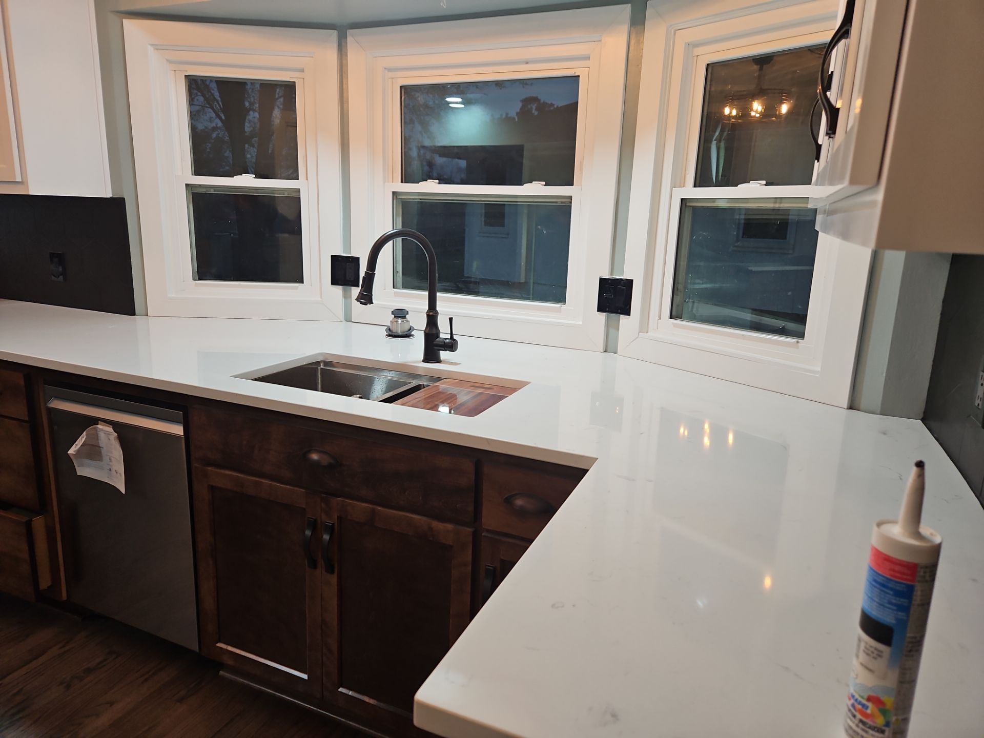 Kitchen with white countertops, dark cabinets, and a window above the sink.