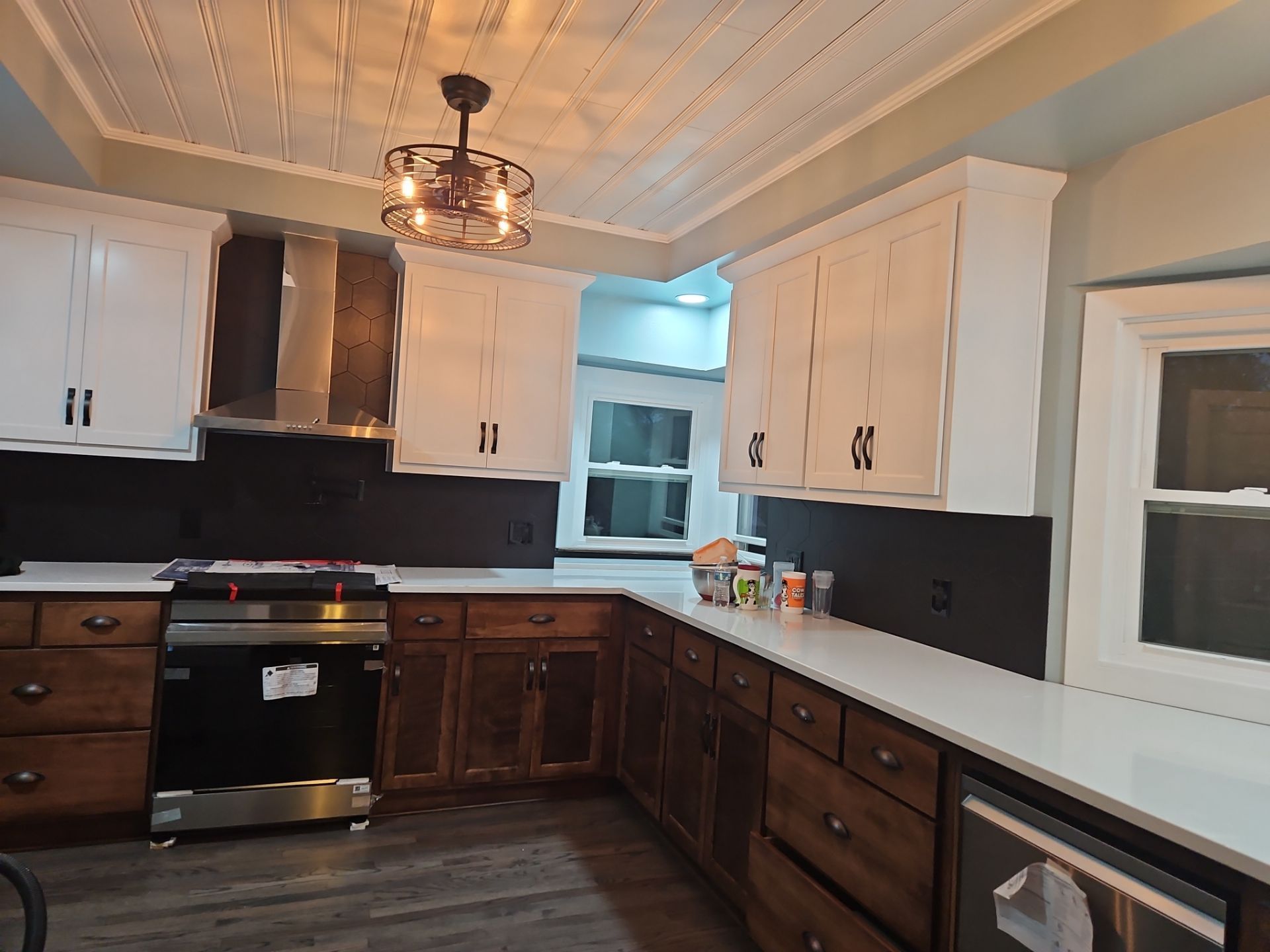Kitchen with white and brown cabinets, stainless steel appliances, and a patterned ceiling.