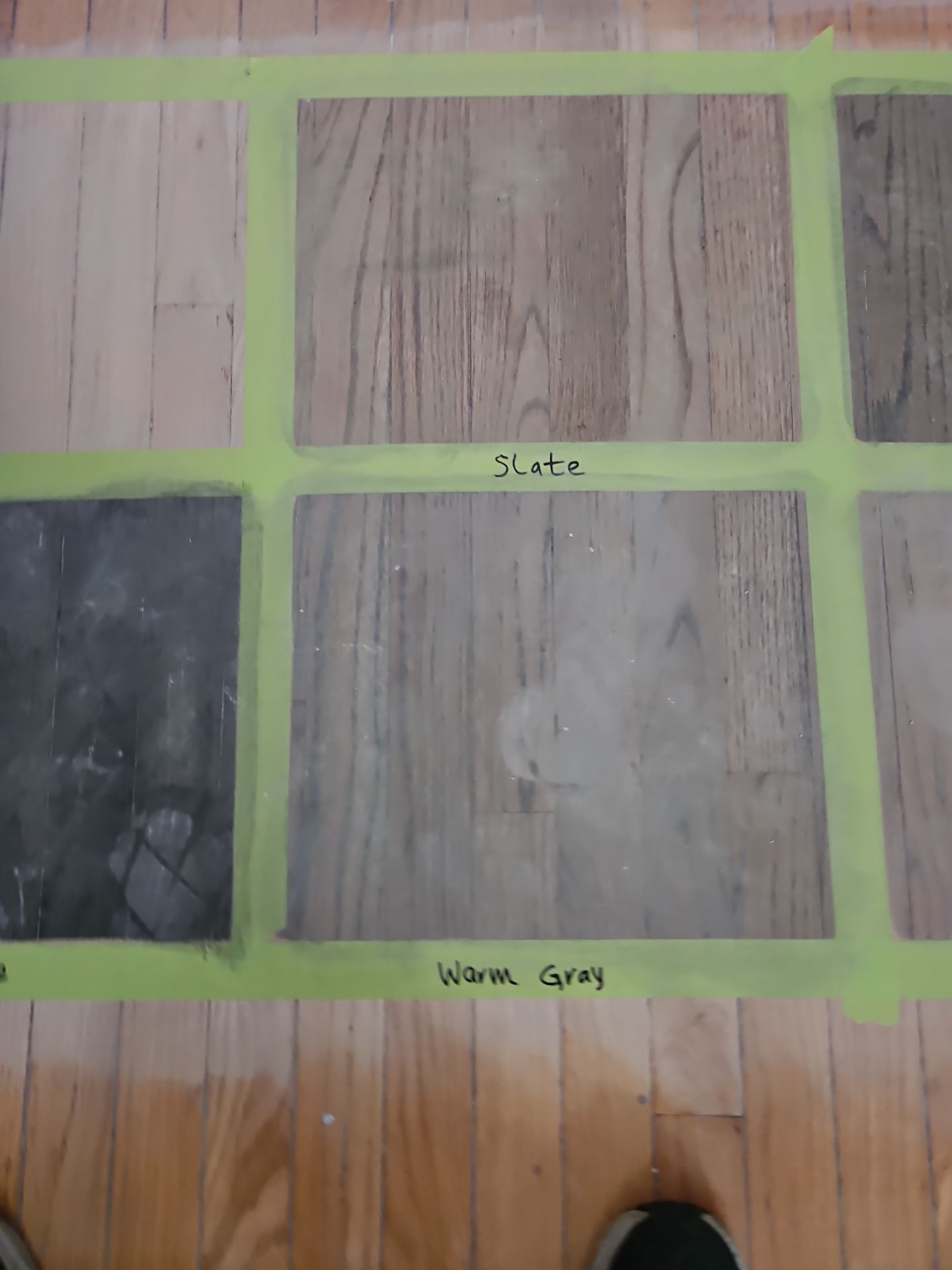 Wood floor samples in slate and warm gray, taped off in green for comparison.