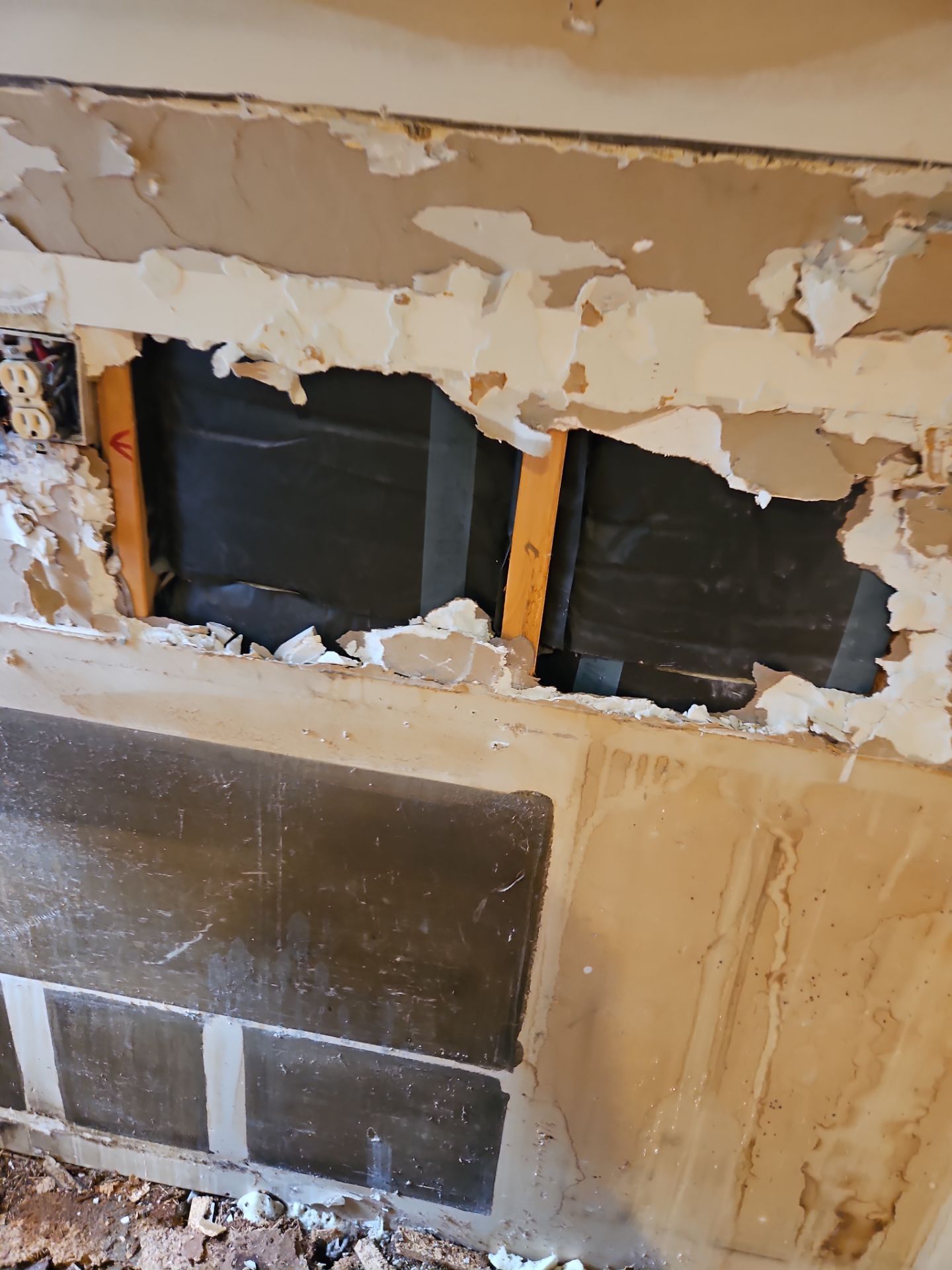 Wall damage: holes in drywall reveal dark material behind, with wooden frames and peeling paint.