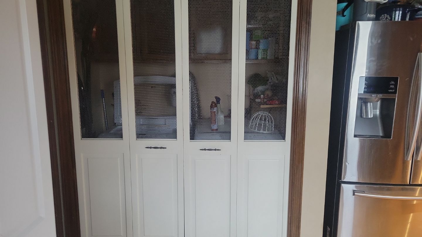 White pantry doors with glass panels; next to a stainless steel refrigerator.