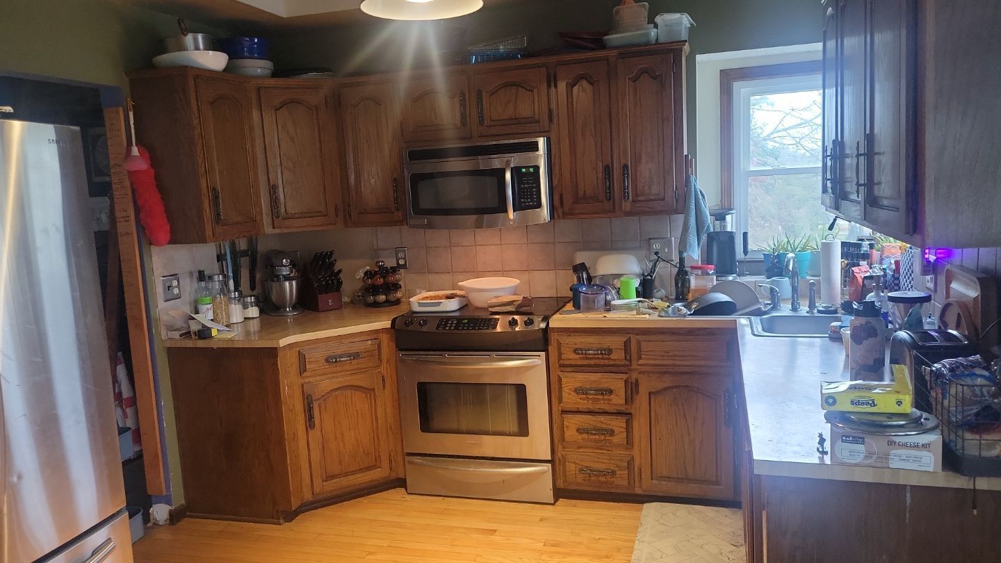 A kitchen with wooden cabinets, stainless steel appliances, and a window.