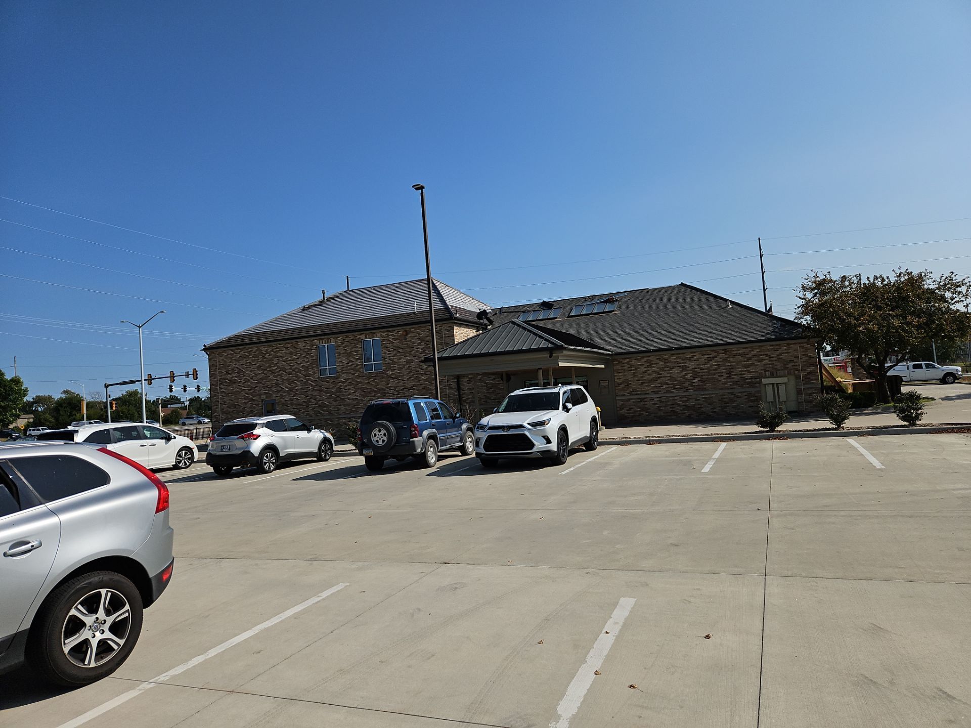 A building with brick exterior and cars parked in front of it under a clear, blue sky.