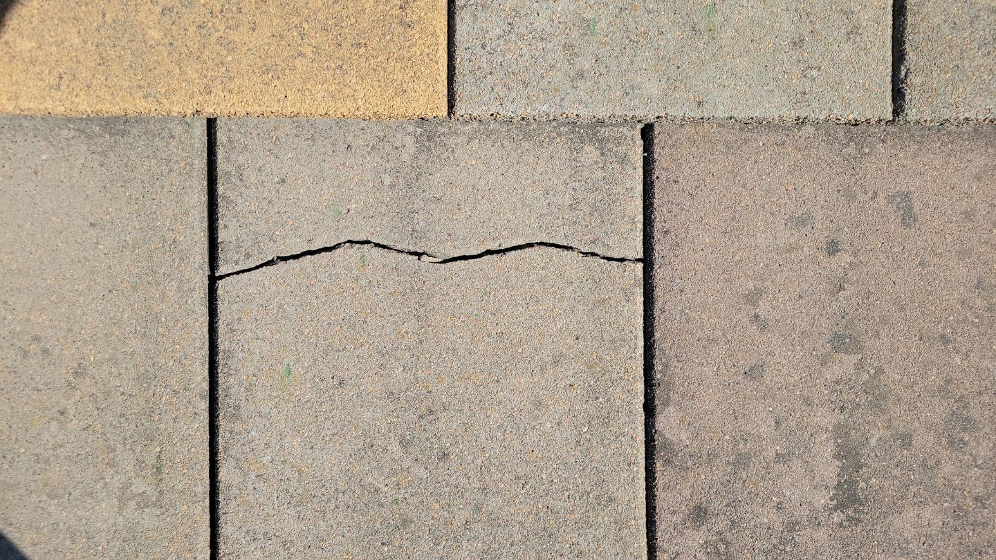Close-up of asphalt shingles with a cracked shingle between two others.