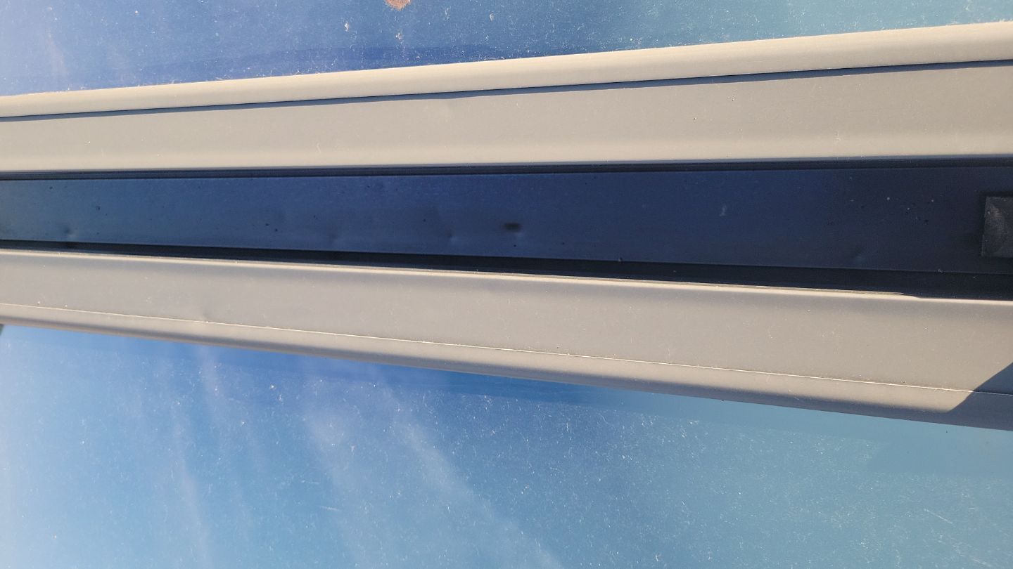 Close-up of a light-colored window frame against a blue sky.