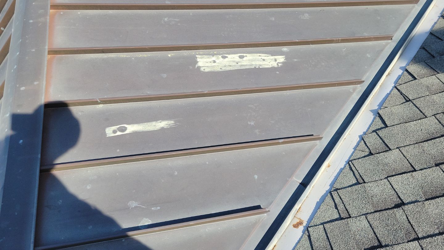Close-up of gray siding and a gray roof's edge. Some paint is peeling on the siding.