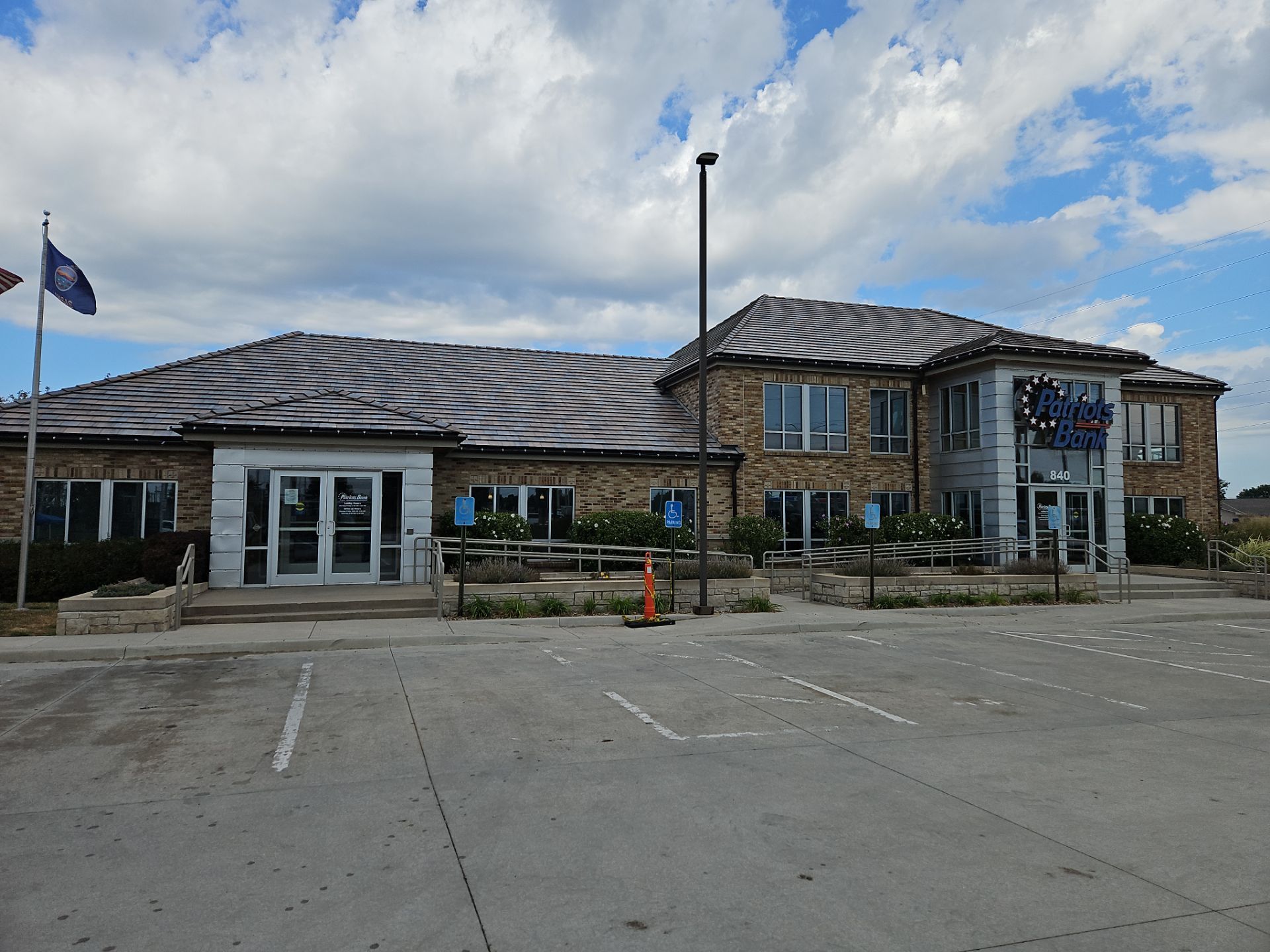 Brick building with glass doors, windows, and parking spaces, under a cloudy sky.