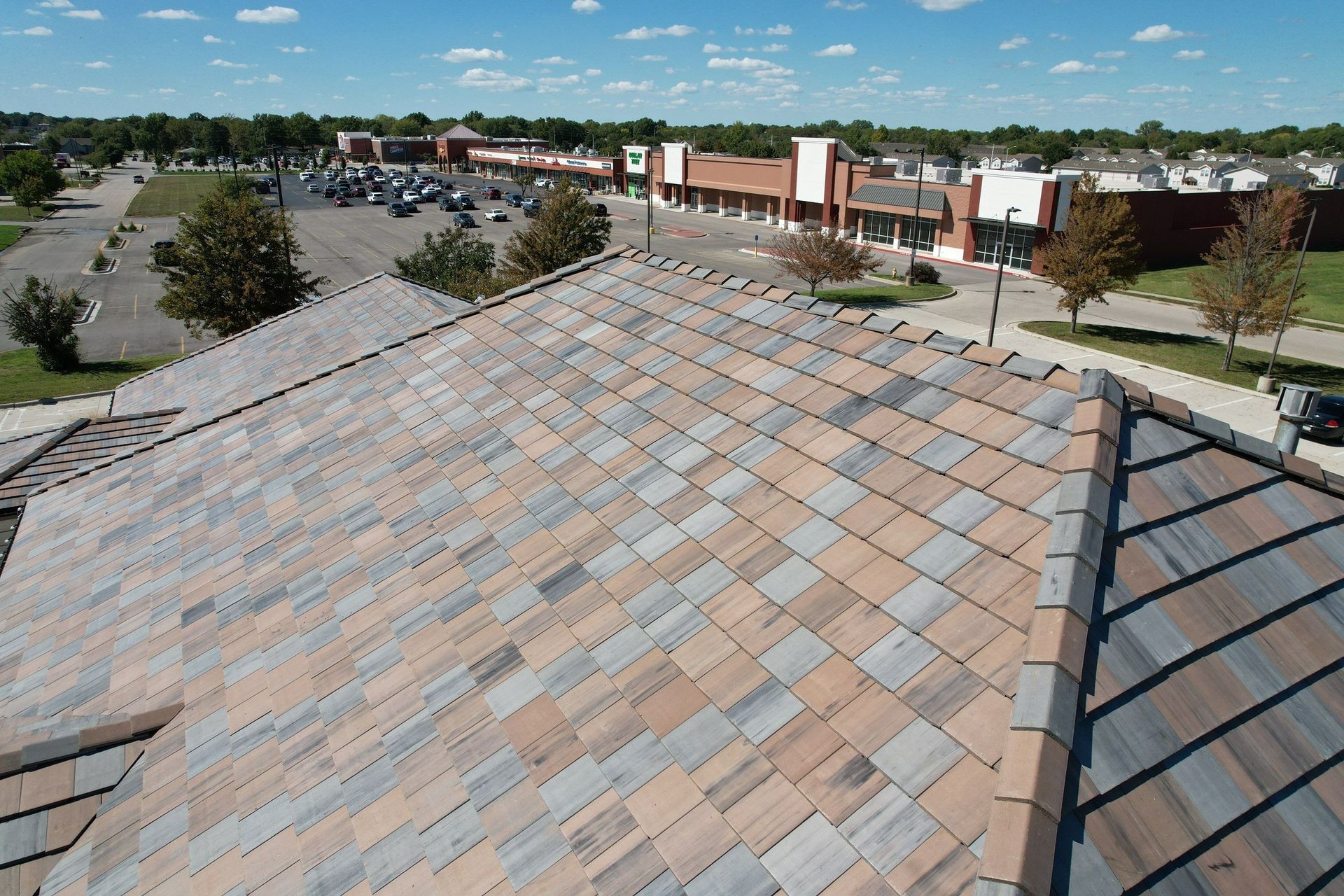View of a multi-colored tile roof with a commercial setting in the background.