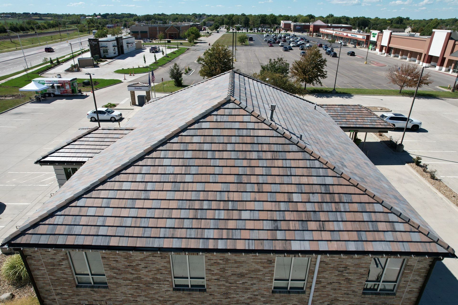 Bird's-eye view of a building with a patterned roof and surrounding parking lot.