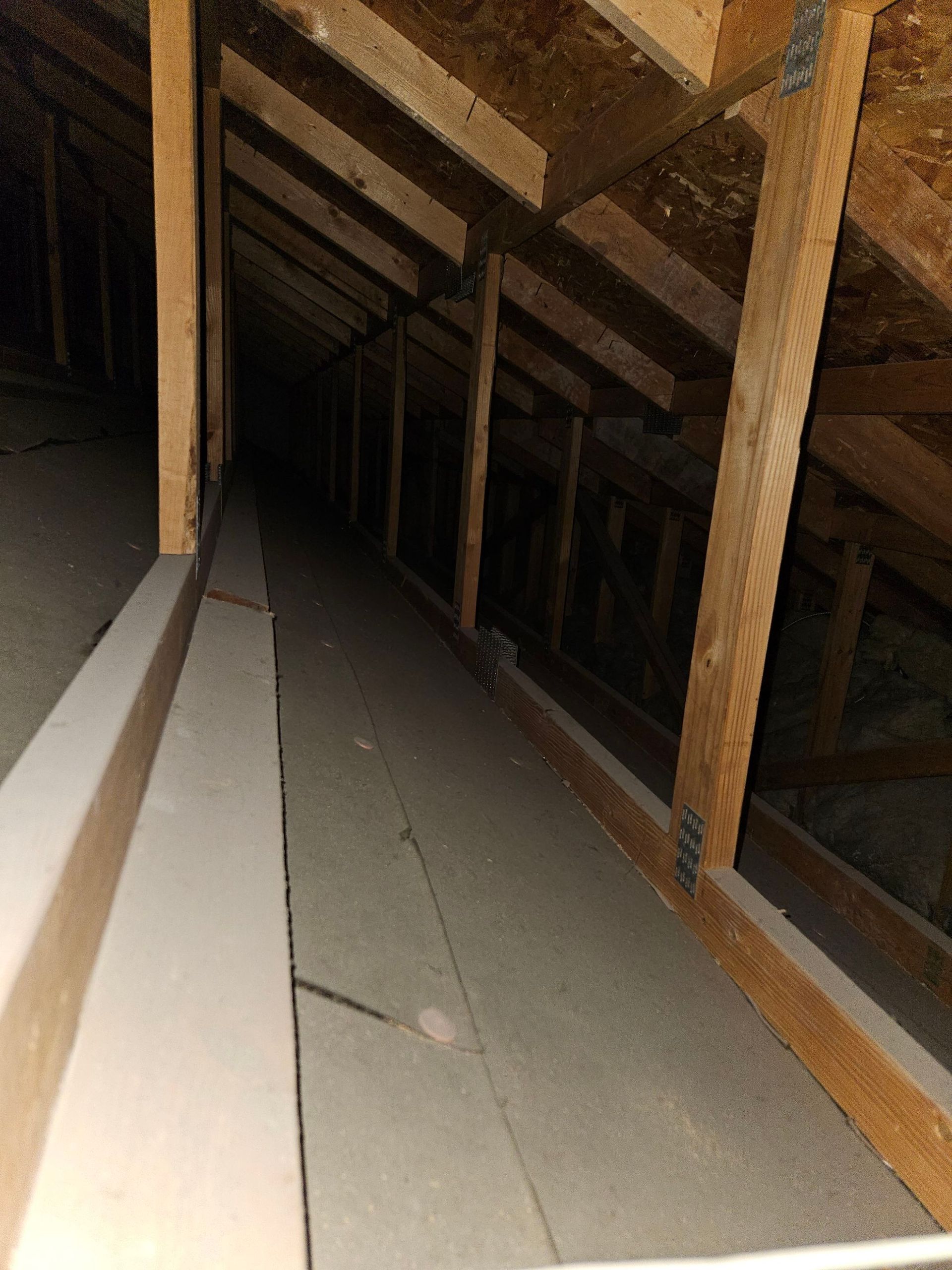 Dark attic space with wooden beams and insulation.