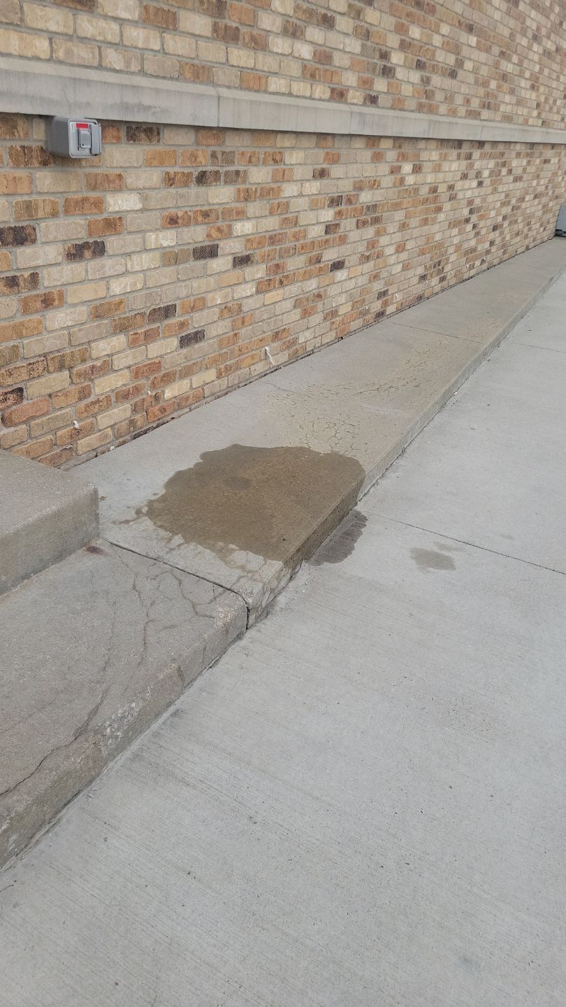 Spilled liquid on a concrete ramp, next to a brick wall.