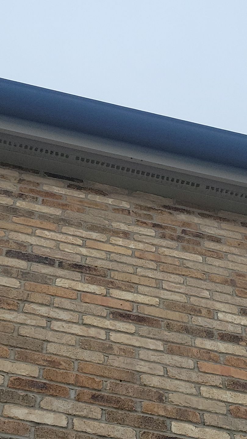 Brick building with dark blue trim and a cloudy sky.