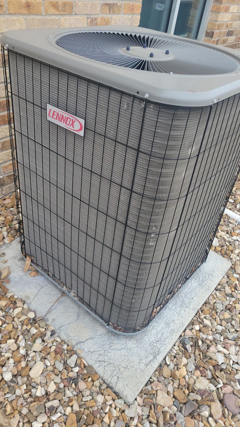 Lennox air conditioning unit outside on a concrete pad, surrounded by rocks.