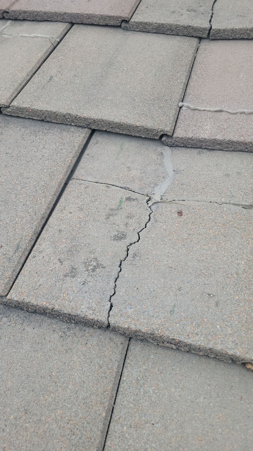 Cracked concrete roof tile, likely damaged, gray color.