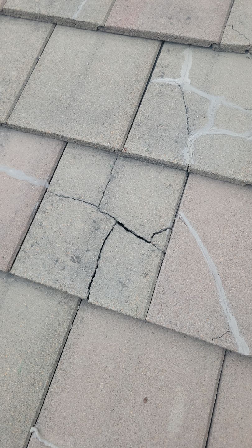 Cracked beige roof tiles with visible fissures, suggesting potential water damage.