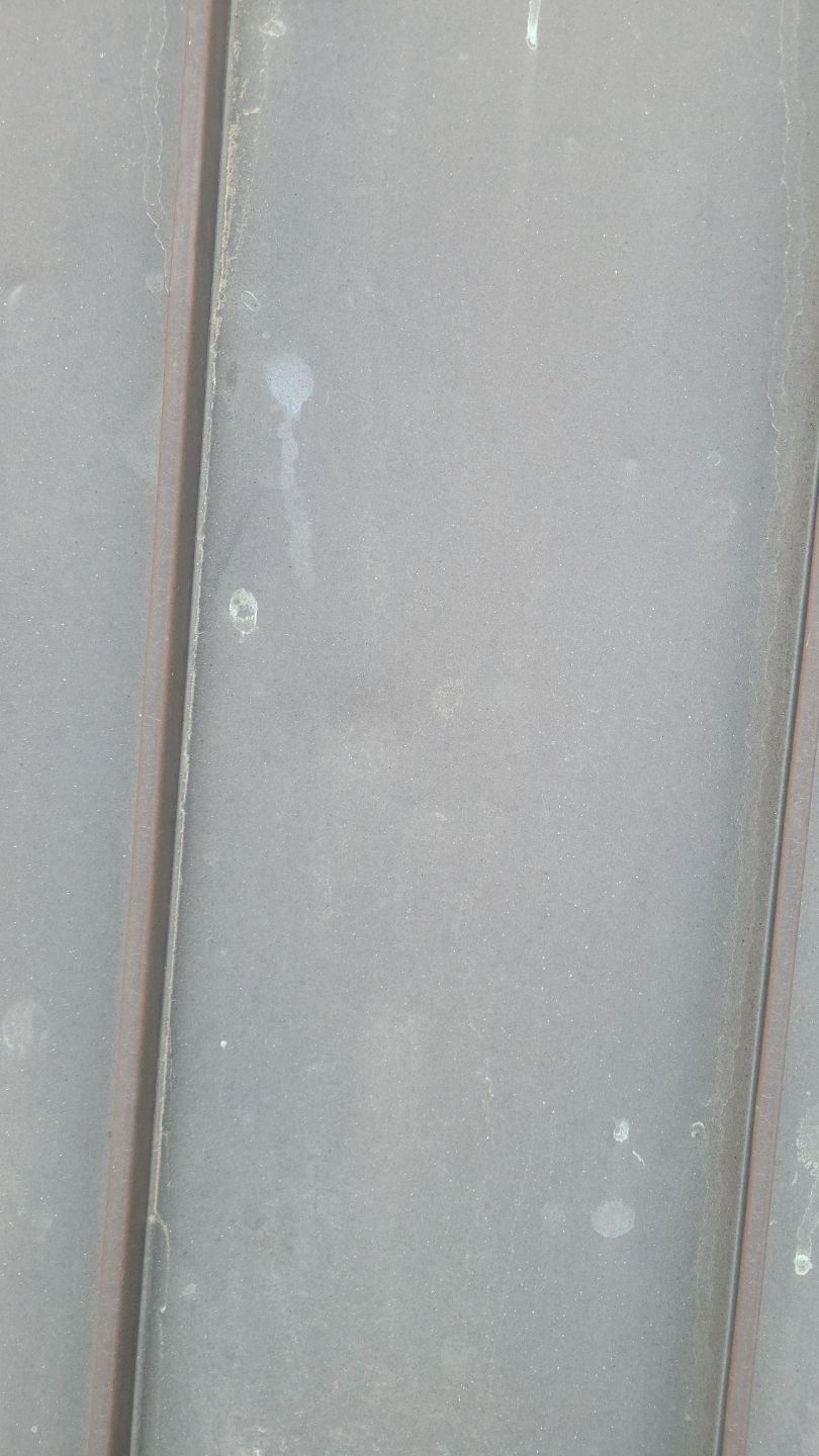 Close-up of gray metal siding with some spotting and a vertical seam.