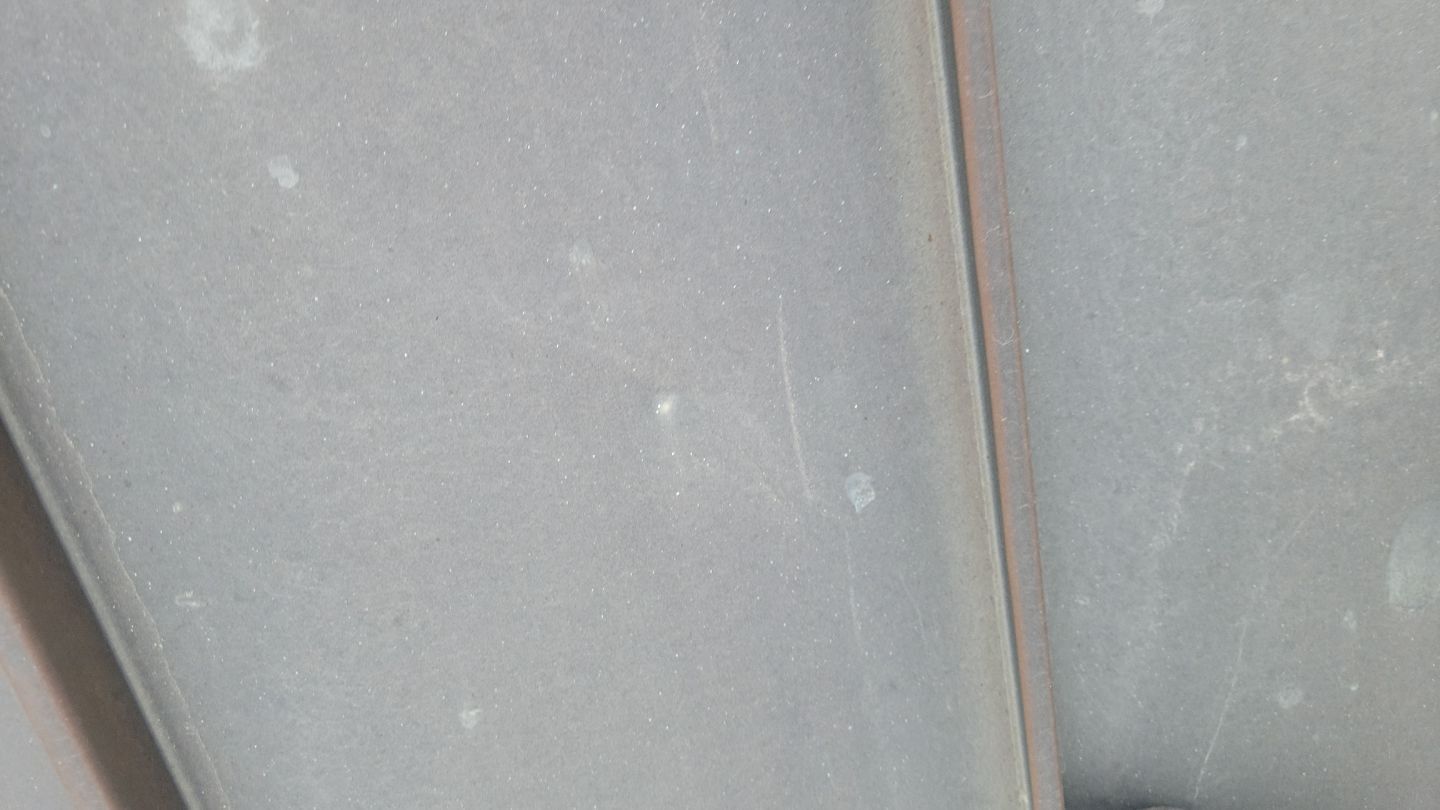 Close-up view of a gray surface with a vertical line dividing it, with scratches and small white spots.