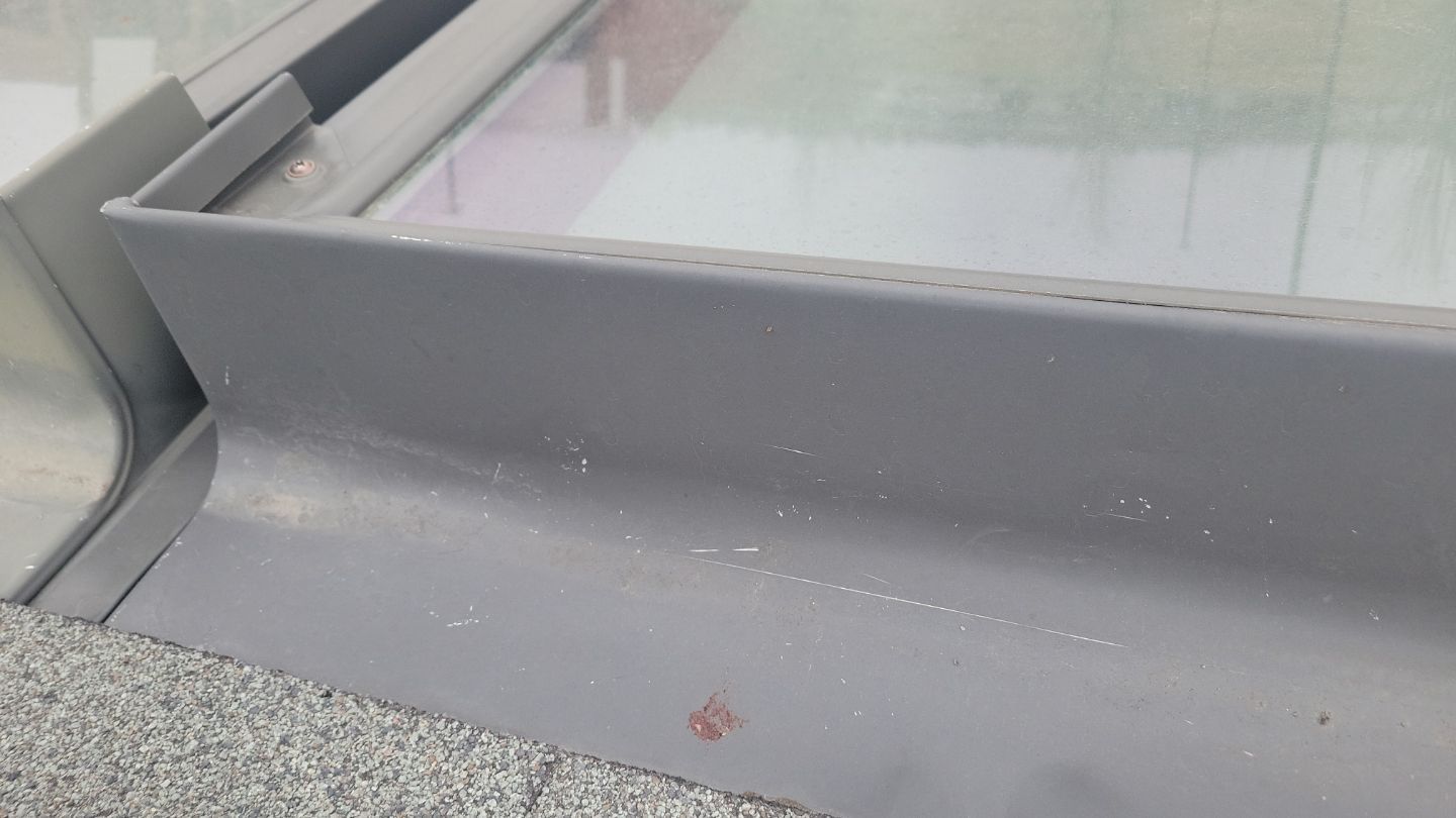 Gray window frame with reflective glass and a concrete surface.