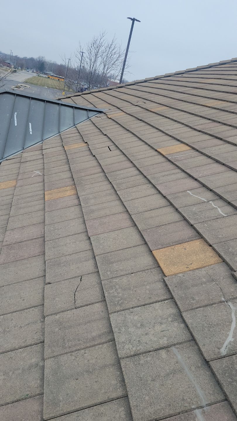 A roof with asphalt shingles, some faded or discolored, and a metal flashing section.