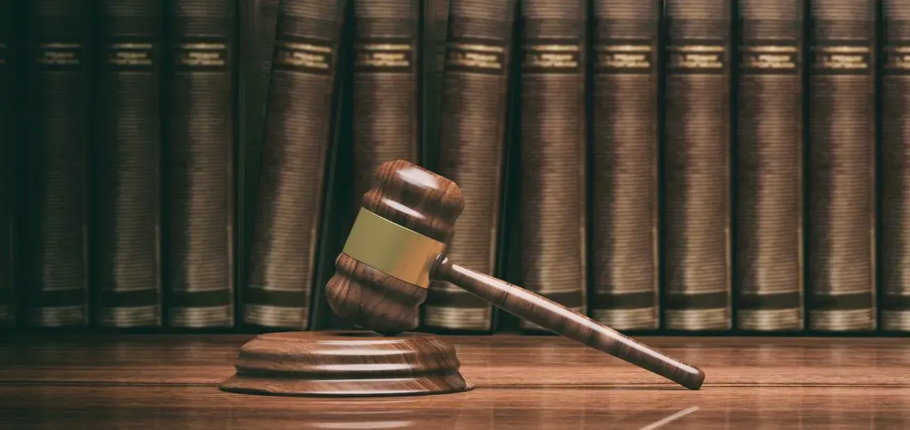 Judge’s gavel resting on a wooden block in front of law books
