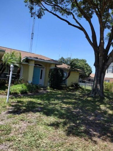 light yellow house with large tree