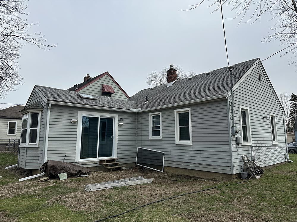 The back of a house with a gray siding and a gray roof.