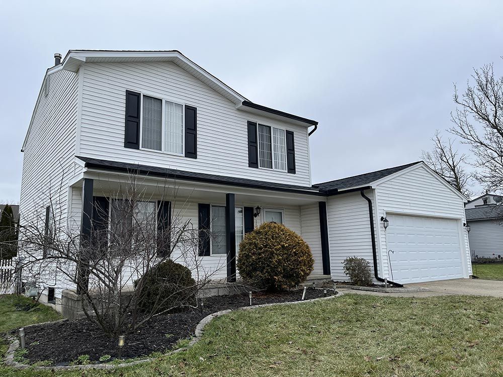 A large white house with black shutters and a garage.