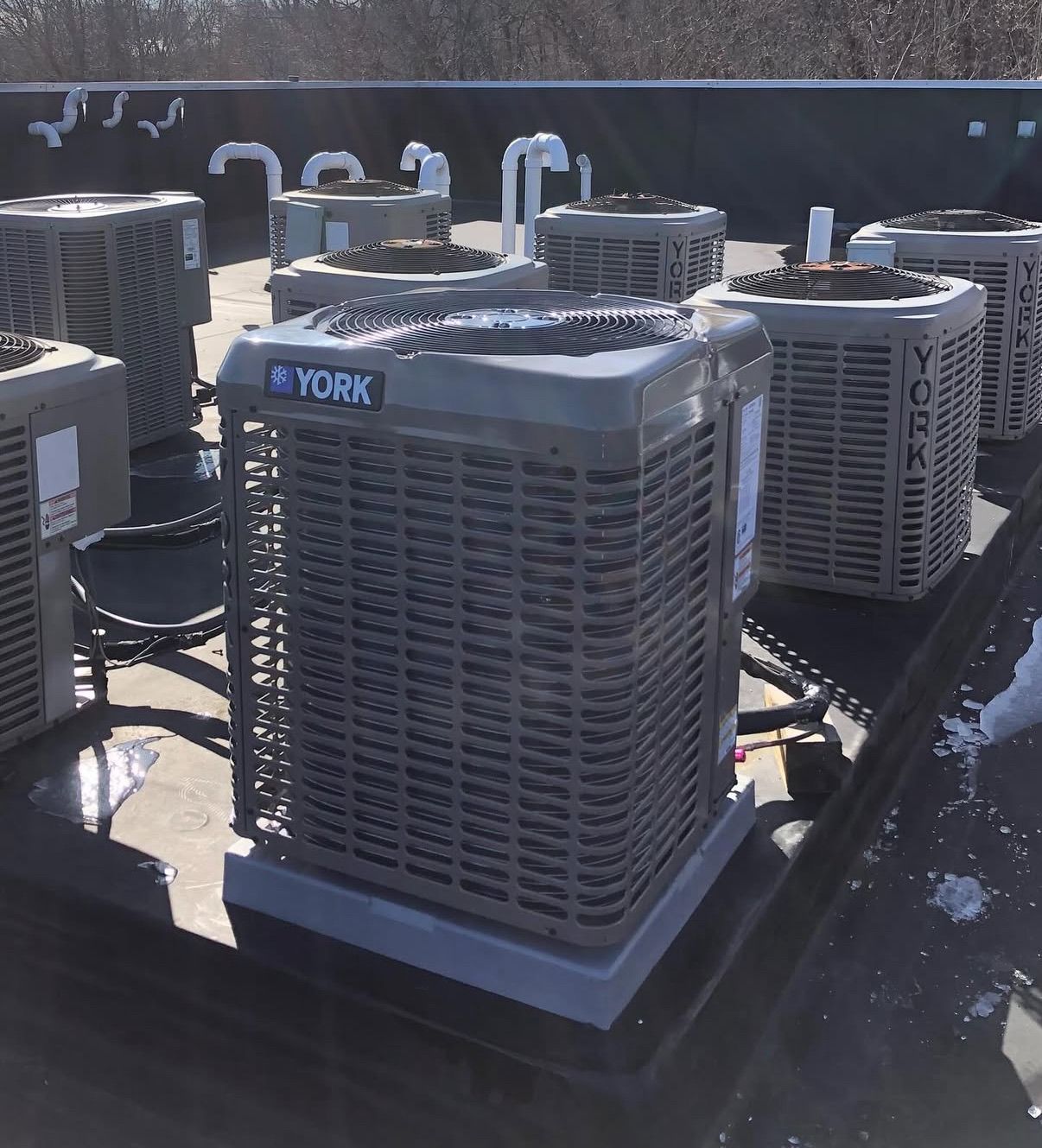 Multiple York air conditioning units are arranged on a flat, dark roof