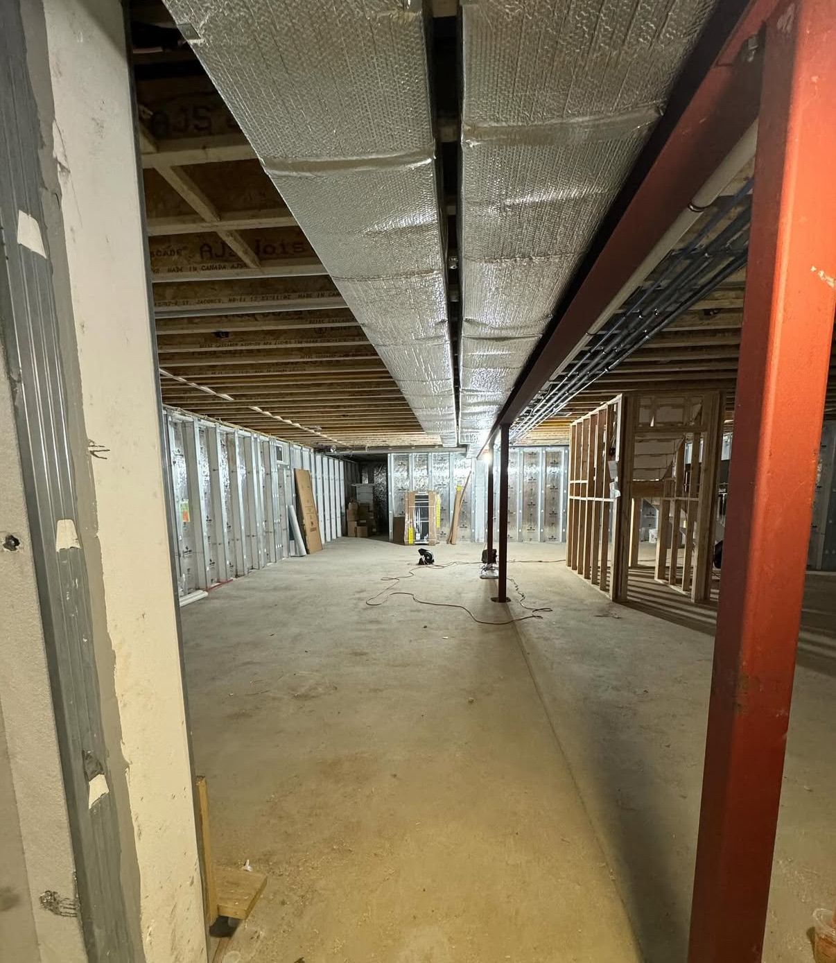 An exposed ceiling insulation in a basement-level space