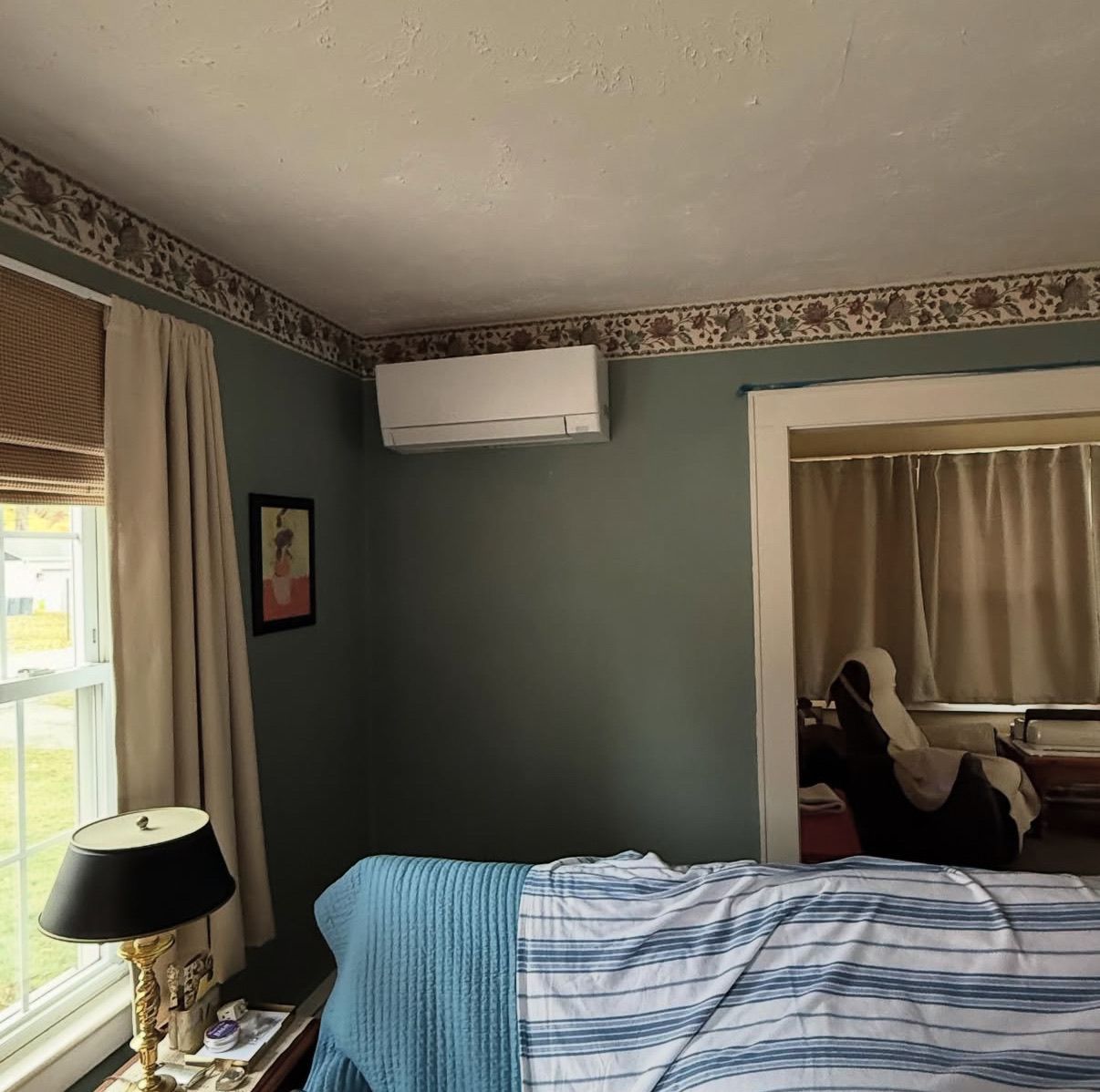 A bedroom with blue-gray walls, a mini-split AC unit