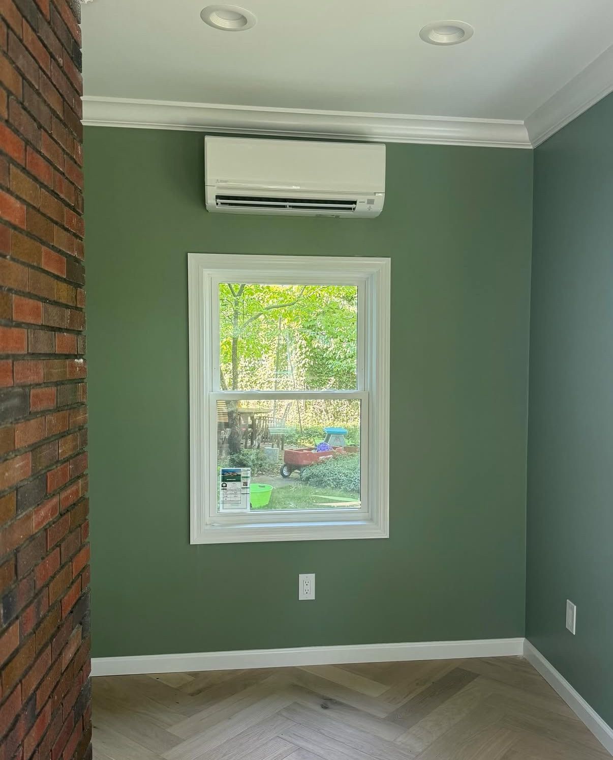 A wall-mounted AC unit on a room with green walls