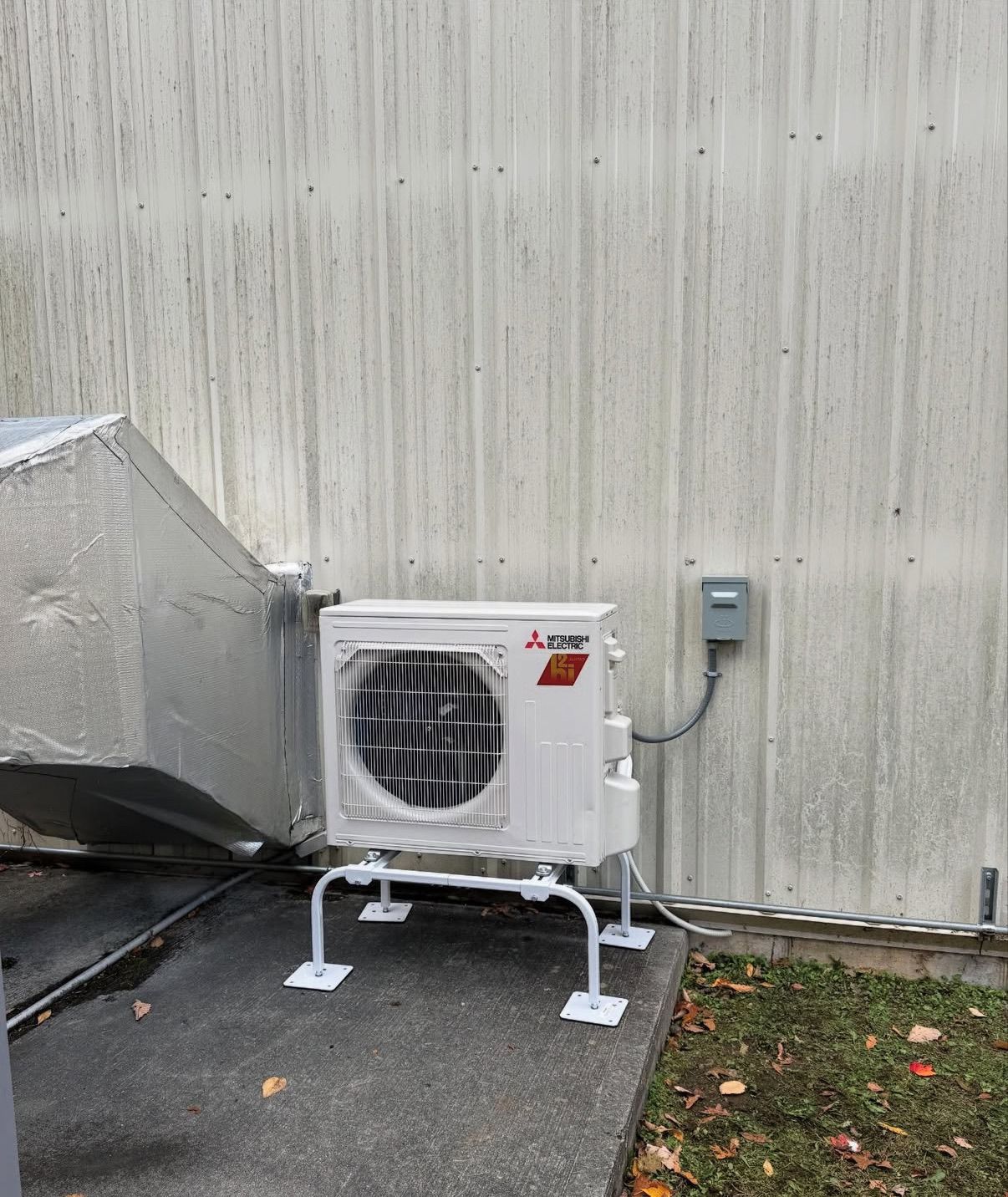 A white Mitsubishi mini-split outdoor HVAC unit