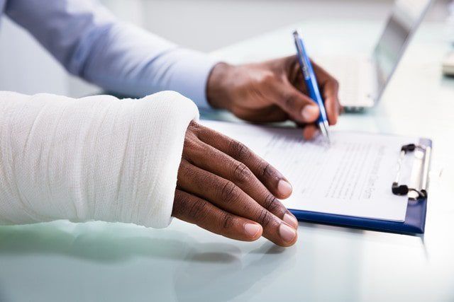 A person wears a blue arm sling supporting a white cast on their forearm.