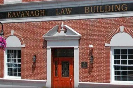 Kavanagh Law Building with red brick facade, arched windows, and a wooden door.