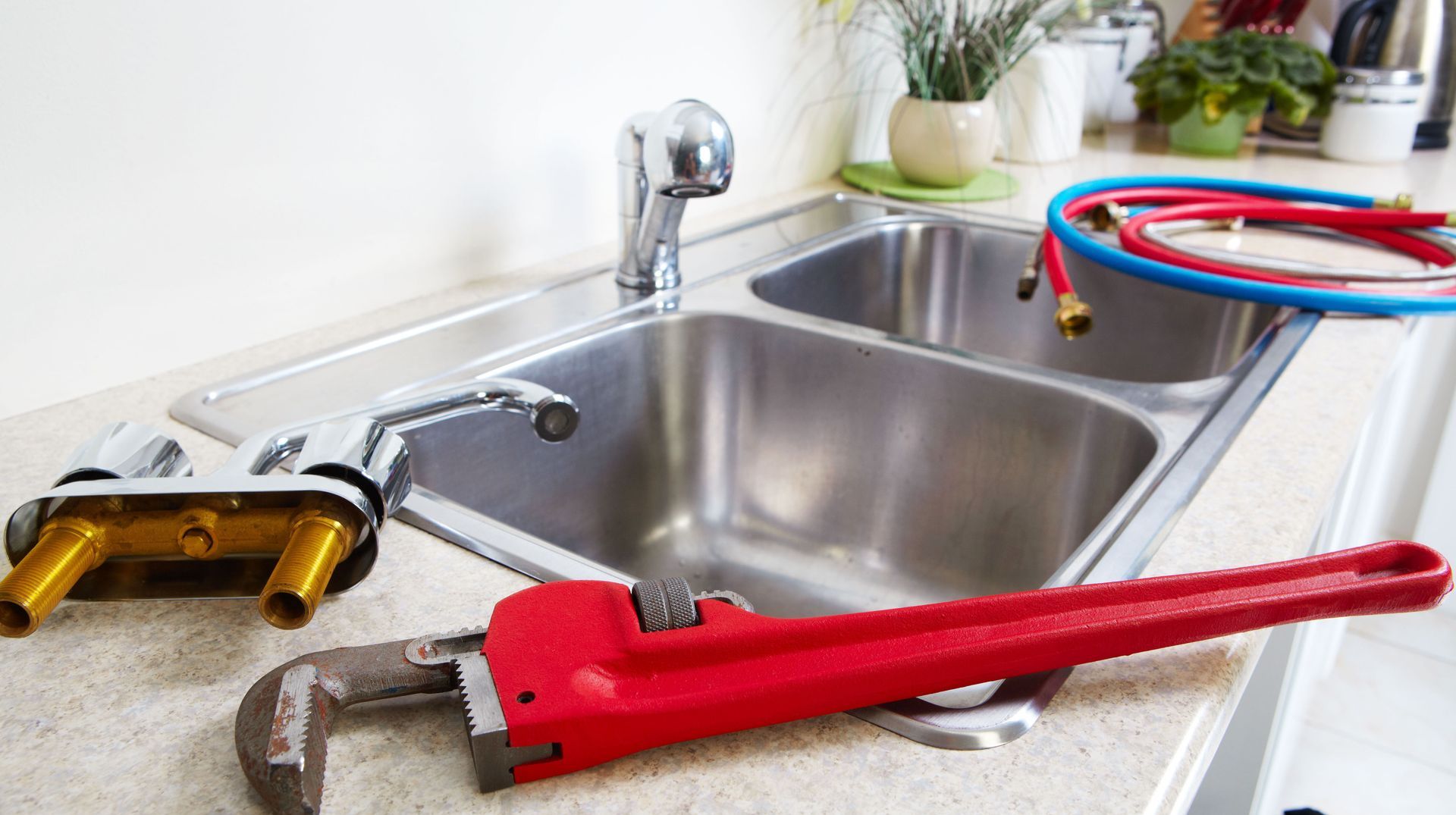 A red wrench is sitting on top of a kitchen sink.