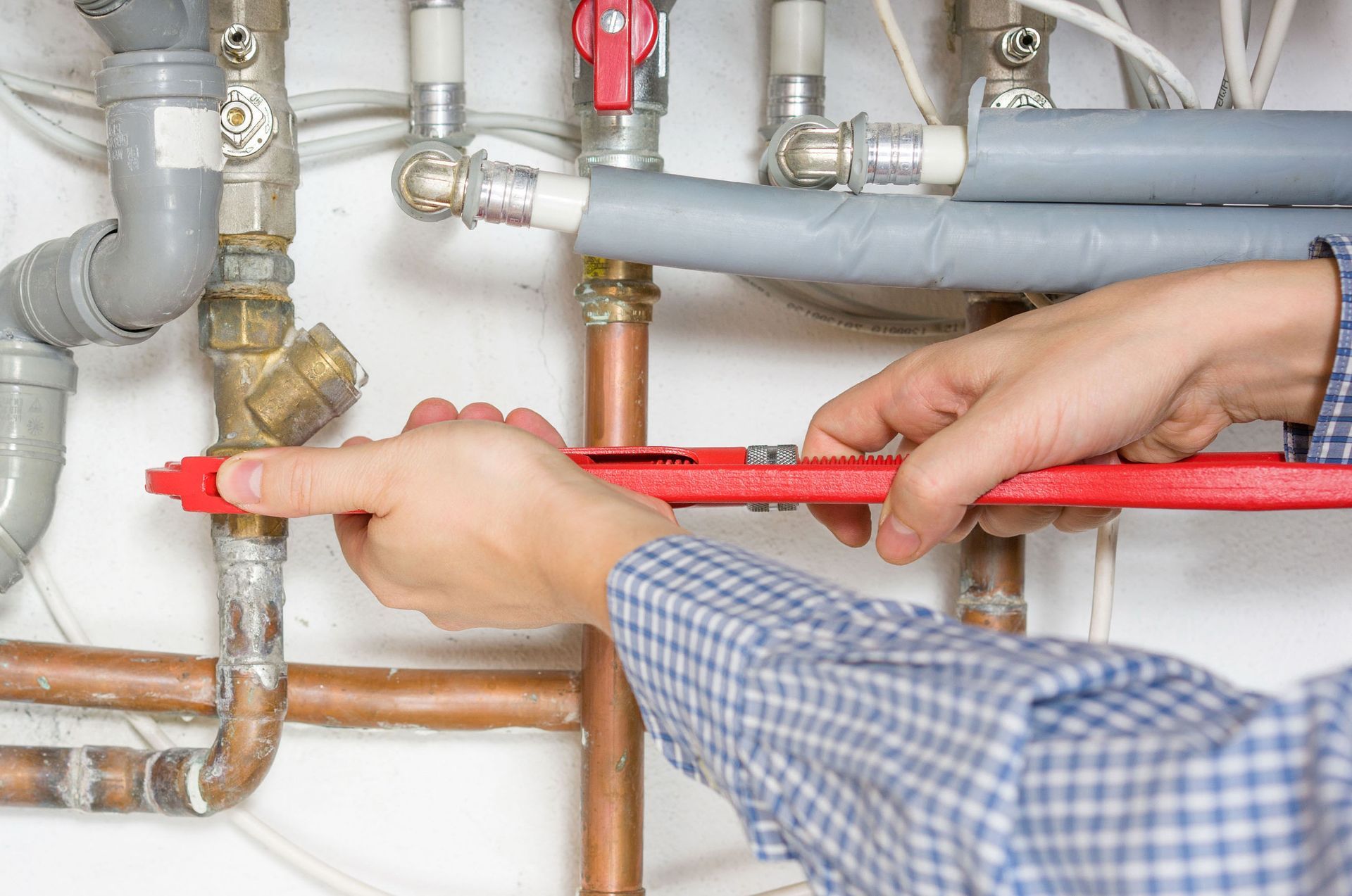 A plumber is fixing a pipe with a wrench.