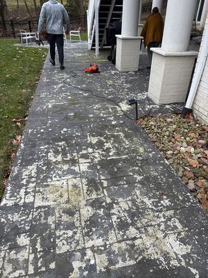 Person walking on chipped, peeling painted brick walkway next to a house with white columns.