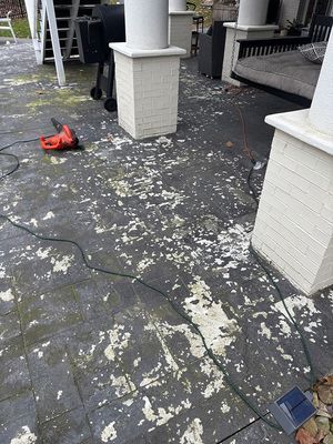 Patio with peeling paint, power tool, columns. Dark grey surface with white flakes.