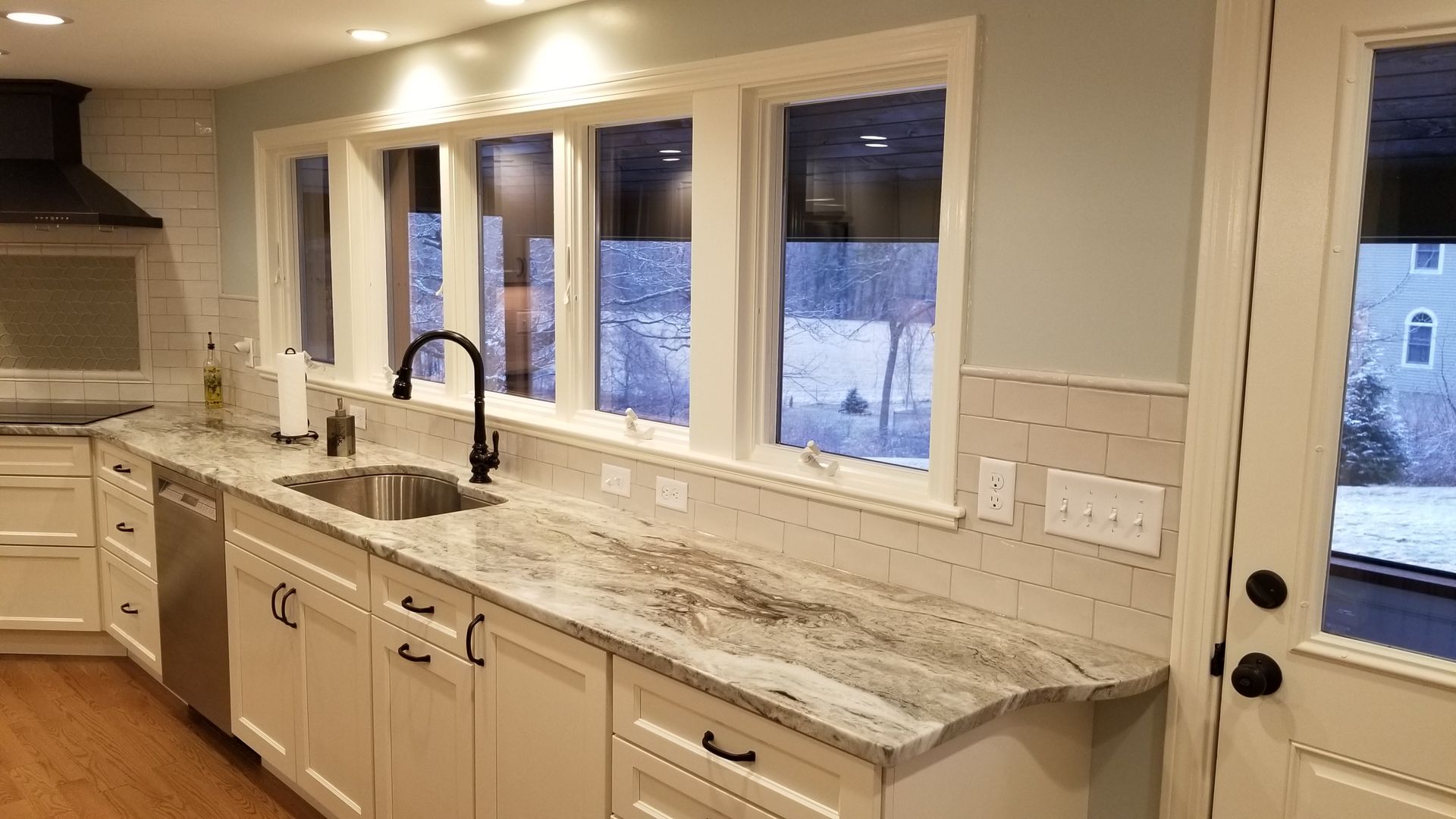 A kitchen with white cabinets , granite counter tops , and stainless steel appliances.