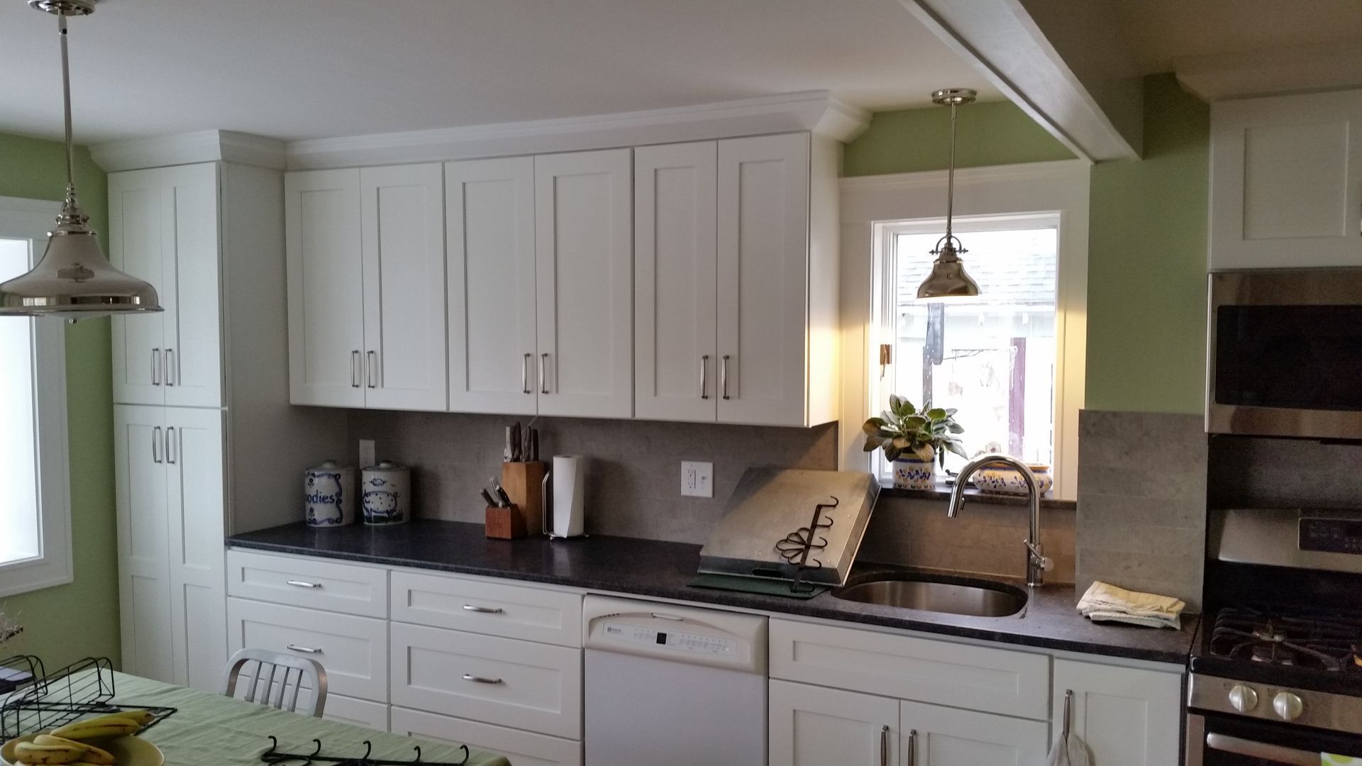 A kitchen with white cabinets and black counter tops