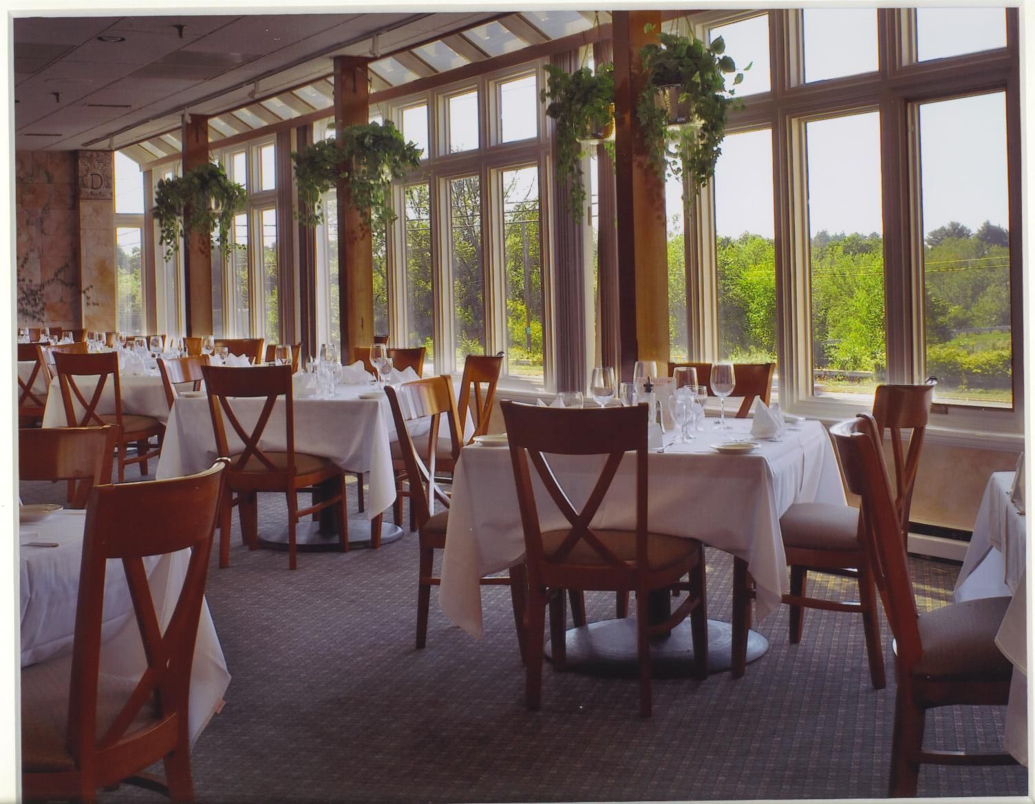 A dining room with tables and chairs and lots of windows