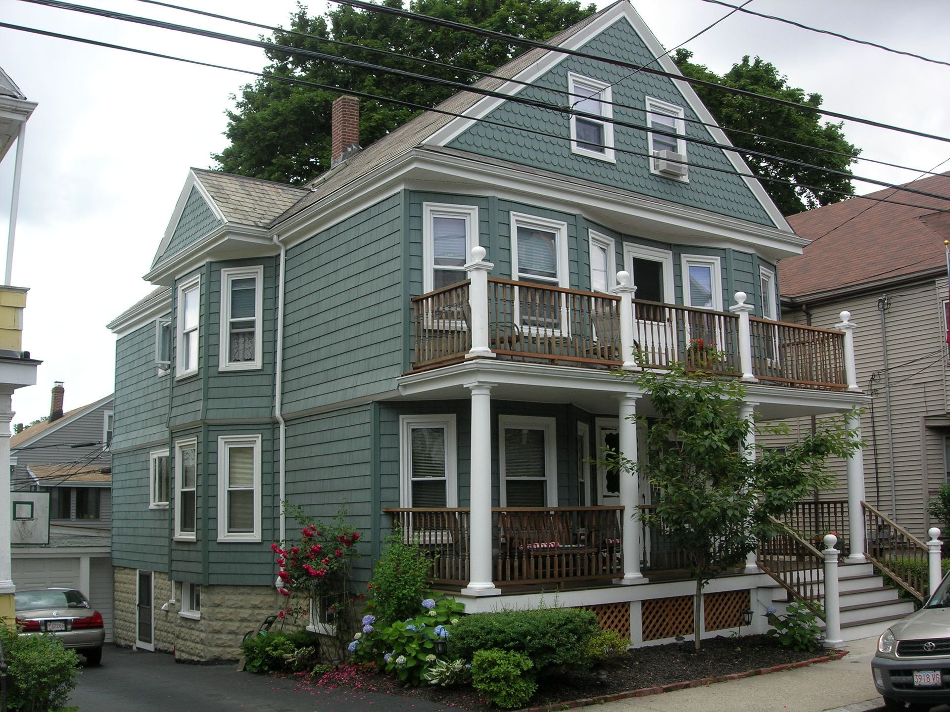 A green house with a porch and a car parked in front of it