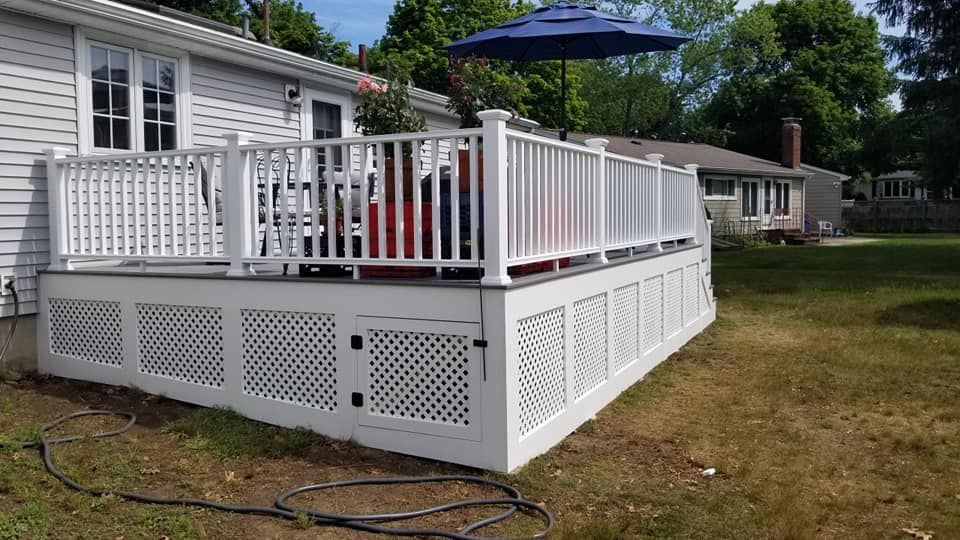 A white deck with a blue umbrella in front of a house.